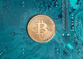 Jasien, Poland, 18 February 2021: Golden bitcoin replica on computer circuit board. This file is cleaned and retouched.